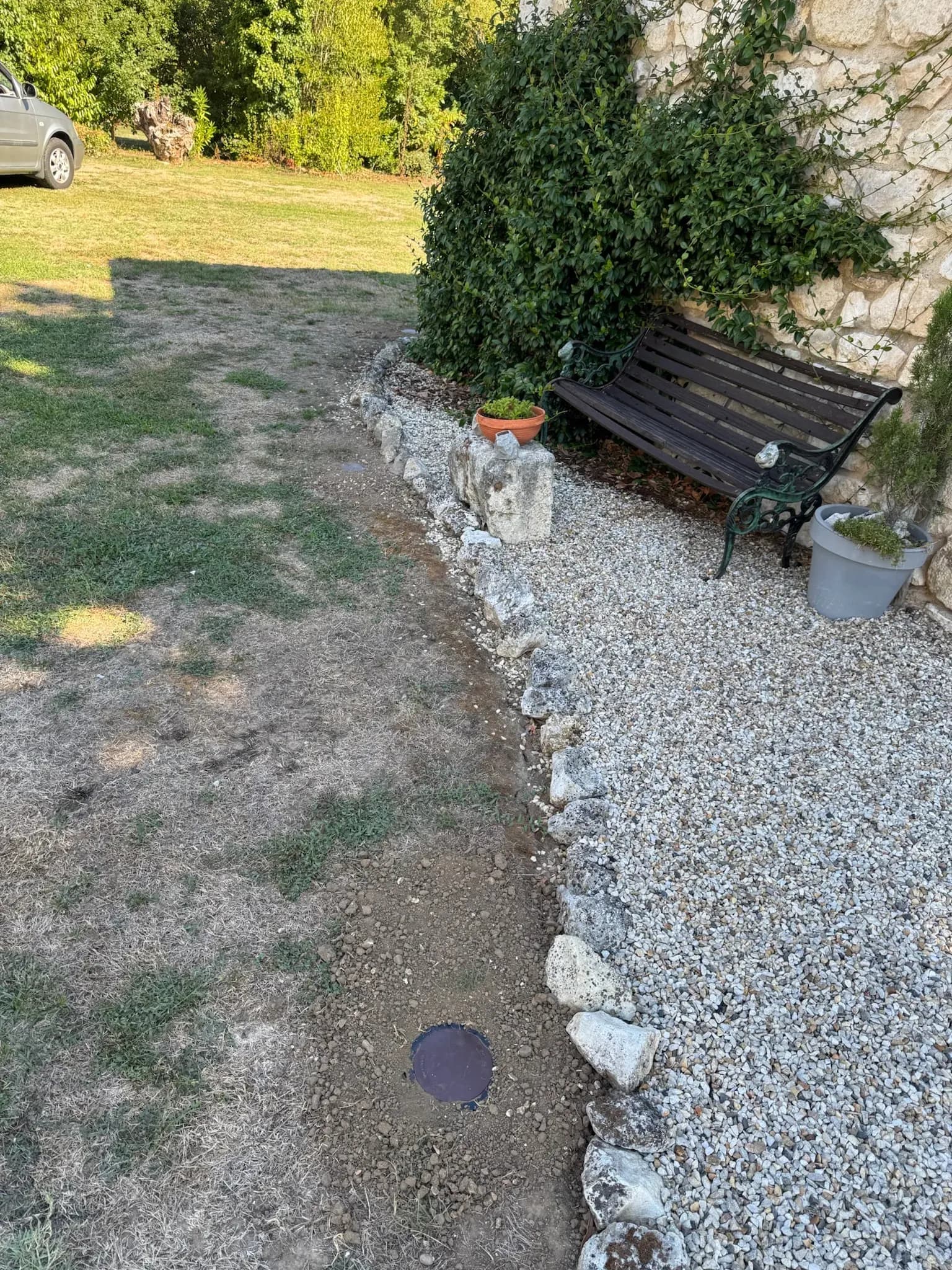 Station d'appâtage à termites enterrée dans la bande de terre entre la pelouse et la cour gravillonnée à Port-Sainte-Foy-et-Ponchapt