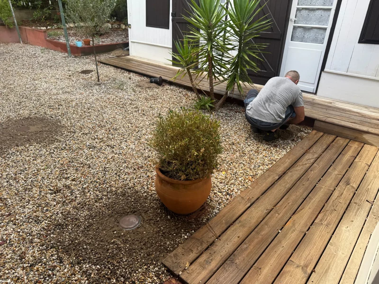 Technicien Savio Protection Bois posant une station d'appâtage dans les graviers le long d'une terrasse bois à Lège-Cap-Ferret