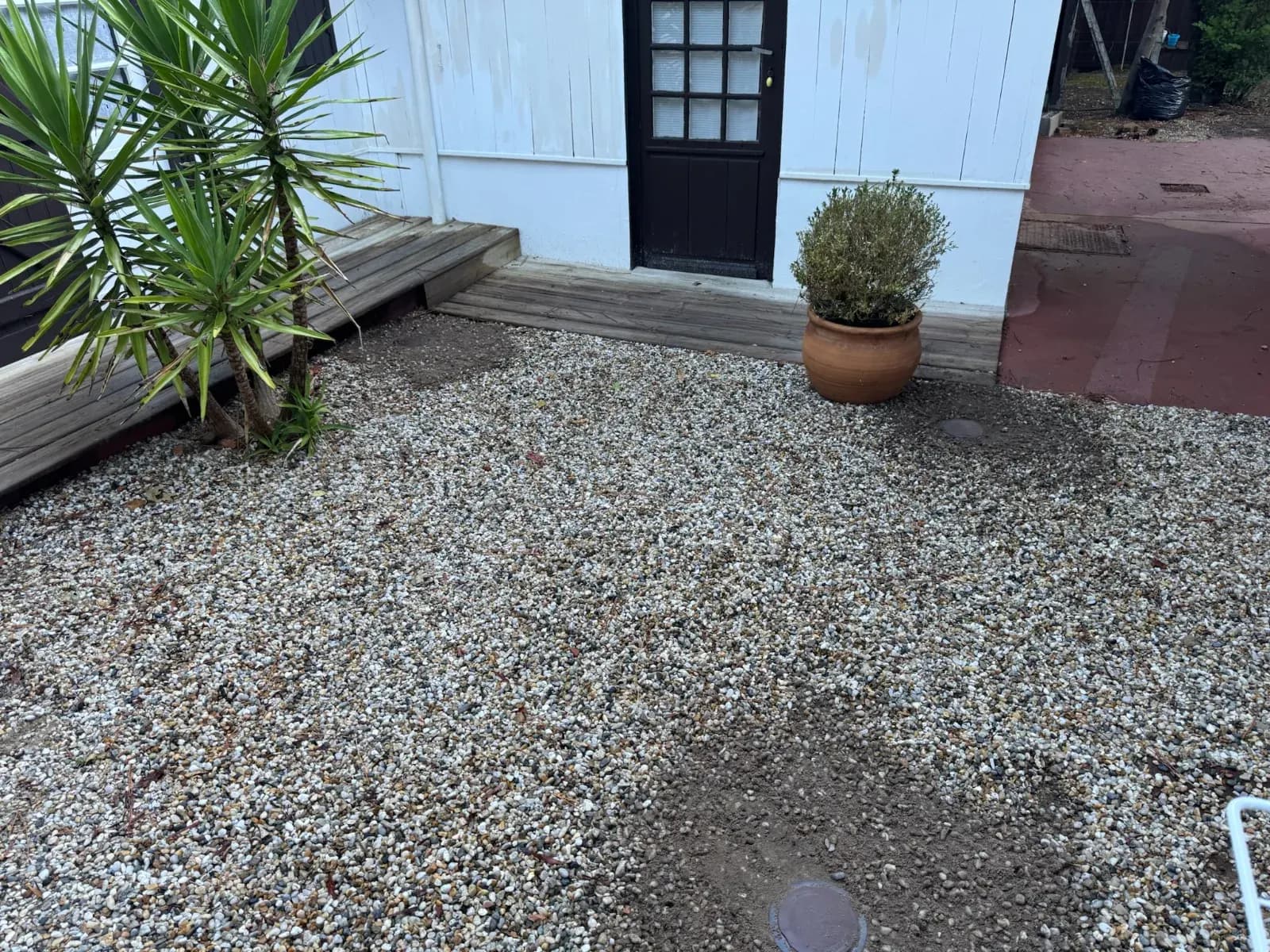 Stations d'appâtage anti-termites affleurantes dans les graviers devant une dépendance blanche à Lège-Cap-Ferret