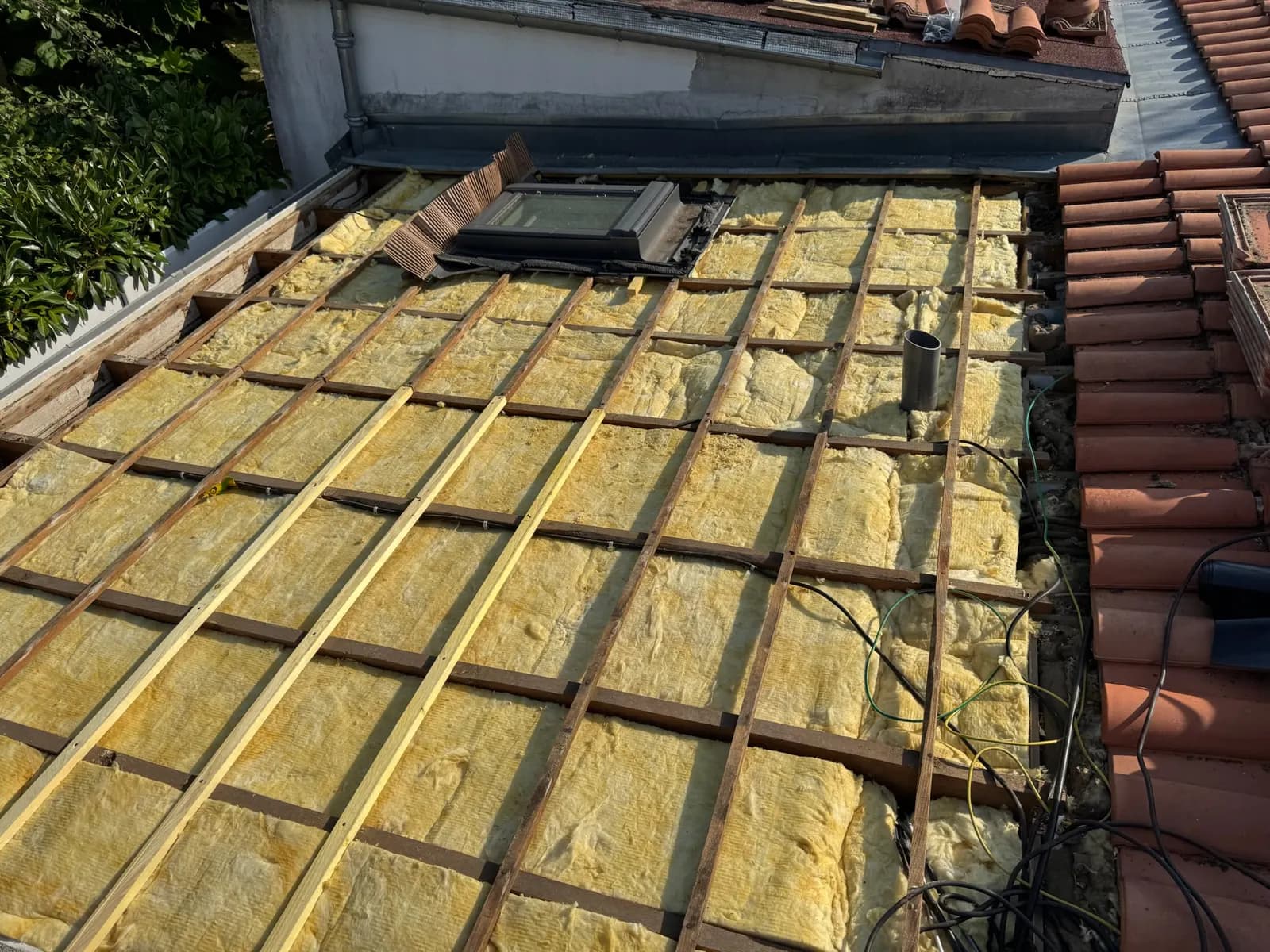 Toiture ouverte avec isolant neuf posé entre les chevrons et fenêtre de toit à Andernos-les-Bains