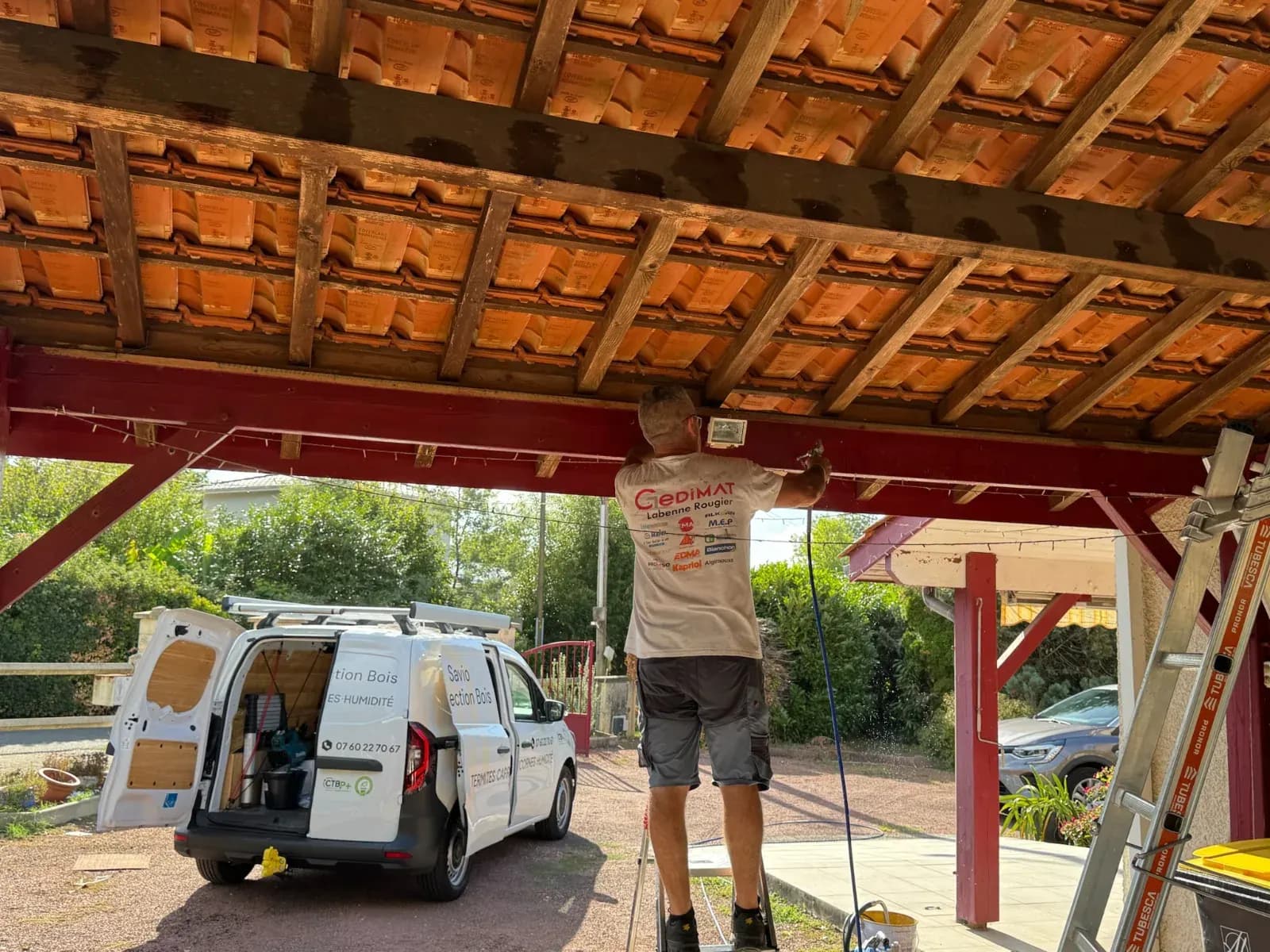 Traitement de la sous-face de la couverture en tuiles du carport à Saint-Selve depuis un escabeau