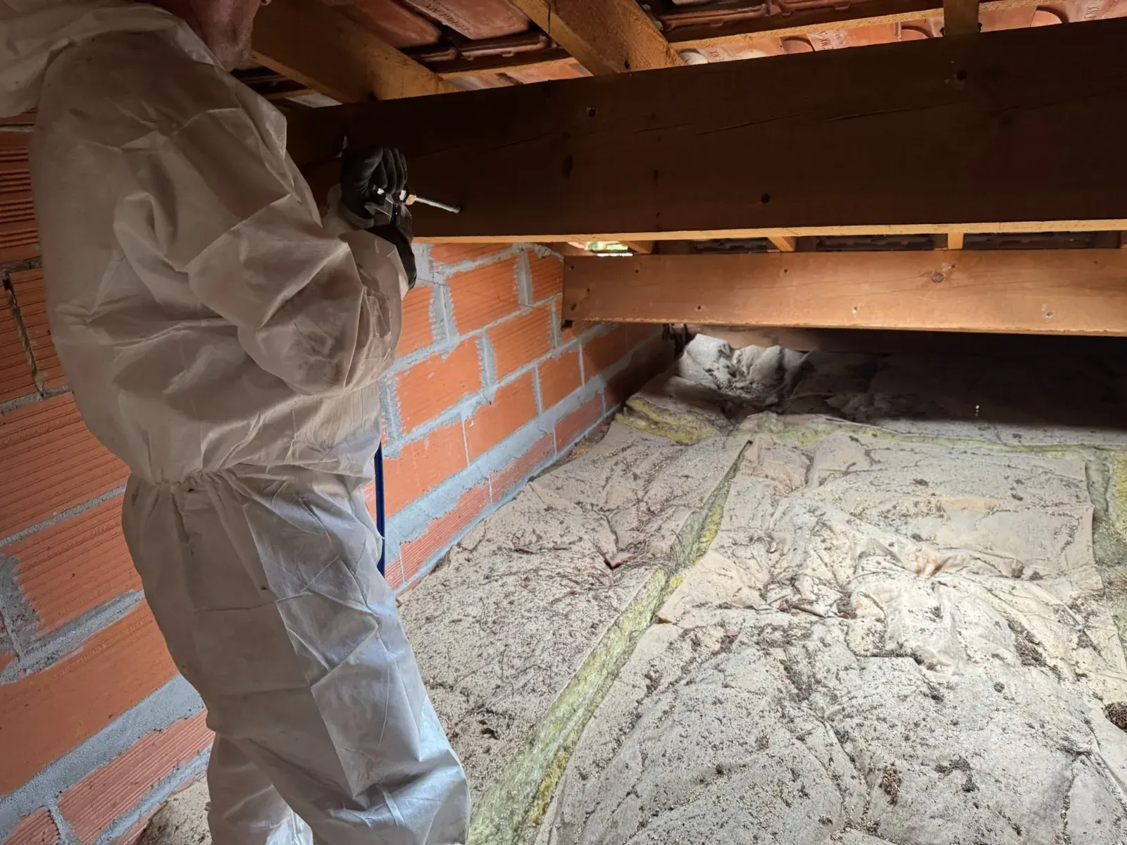 Technicien en combinaison de protection injectant la charpente d'un comble à Gujan-Mestras